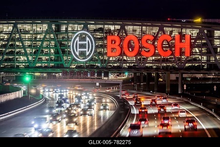 A8 motorway at Stuttgart Airport with Bosch multi-storey car park in the evening, cars create light trails. The 440 metre long construction offers space for 4200 vehicles. Bosch owns the naming rights, the stylised ignition anchor measures 12 metres in diameter. This makes it one of the largest neon signs in the world. Stuttgart, Baden-Württemberg, Germany-stock-foto