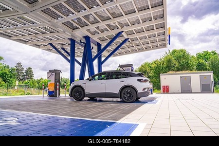 White car at a modern charging station with solar cells, surrounded by green trees, ENBW Ladepark, Rutesheim, Germany-stock-foto