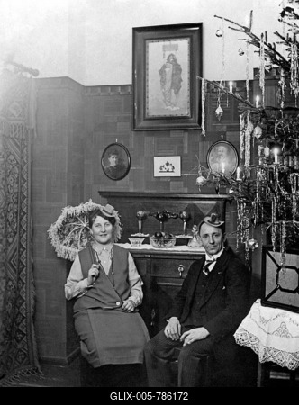 Couple celebrates Christmas in the living room next to the Christmas tree, around 1920, Germany-stock-foto