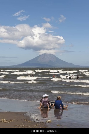 People sitting on the shallow shore of Lago de Nicaragua with the volcanic island of Ometepe and the stratovolcano Volcán Concepción at back, San Jorge, Nicaragua, Central America-stock-foto