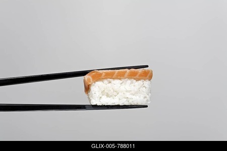 Black chopsticks holding nigiri sushi with grilled salmon-stock-foto