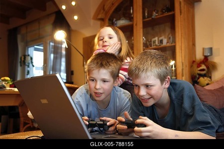 Siblings, 7, 11, 13 years old, with laptop computer in the living room, playing a car racing computer game-stock-foto