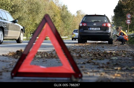 Warning triangle, car breakdown, female driver has stopped on the hard shoulder of a country road, wearing a reflective vest, changing a defective wheel-stock-foto