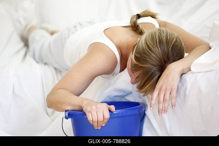Woman is vomiting into a bucket, nausea, sickness-stock-foto