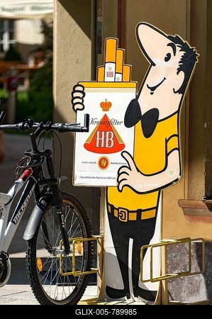 Bicycle stand with the HB-M舅nchen advertising character, HB brand of cigarettes, Mittenwald, Upper Bavaria, Bavaria, Germany-stock-foto