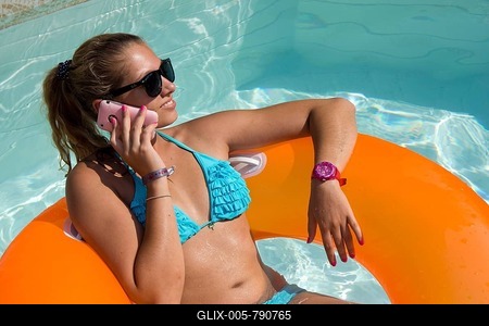 Young woman on an inner tube, floating tyre, talking on a mobile phone in a private swimming pool, Germany-stock-foto