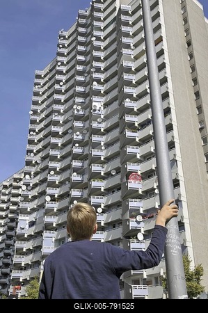 Boy standing in front of a high-rise apartment building with balconies and satellite dishes, satellite town of Chorweiler in Cologne, North Rhine-Westphalia, Germany, Europe-stock-foto