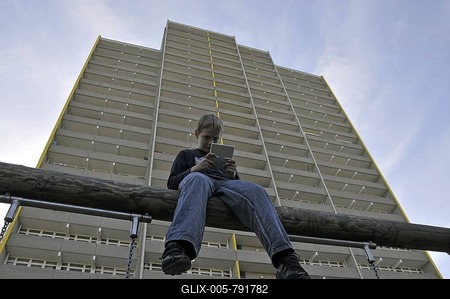 Boy, 9, playing with his Nintendo in front of a high-rise apartment building, satellite town of Chorweiler in Cologne, North Rhine-Westphalia, Germany, Europe-stock-foto