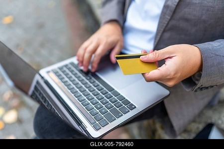 Close-up of a caucasian man shopping online using laptop and credit card sitting on city bench-stock-foto