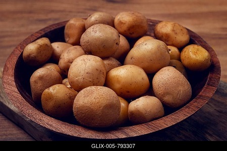 A wooden bowl filled with freshly harvested small potatoes sits on a rustic wooden surface, showcasing their natural earthy tones and textures, perfect for various culinary dishes-stock-foto