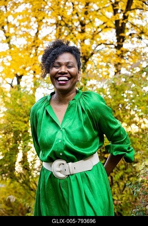 Portrait of a laughing, dark-skinned woman with curls and green dress, outdoor shot in autumn, Germany-stock-foto