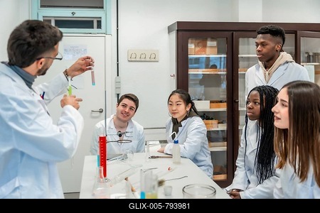 Multi ethnic group of university students attending a chemistry lesson in a laboratory, teacher showing a test tube with a chemical reaction-stock-foto