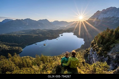 Two (hikers) looking at Eibsee lake at sunrise, sun shining over Bavarian alpine foothills, right Zugspitze, Wetterstein mountains near Grainau, Upper Bavaria, Bavaria, Germany-stock-foto