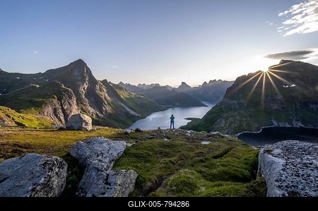 Young woman looking over fjord landscape, sun shining over mountain landscape with fjord Forsfjorden and lake Krokvatnet, Moskenesöy, Lofoten, Nordland, Norway-stock-foto