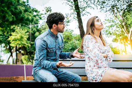 Upset couple arguing in a park. A young couple arguing sitting on a park bench, Concept of couple problems and crisis. Man arguing with his girlfriend sitting in a park-stock-foto