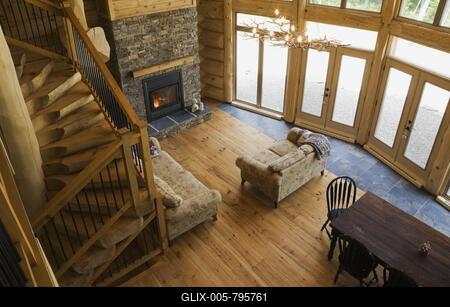 High angle view of wooden and black wrought iron staircase and living room and dining table inside handcrafted Eastern white pine Scandinavian log cabin home, Quebec, Canada-stock-foto
