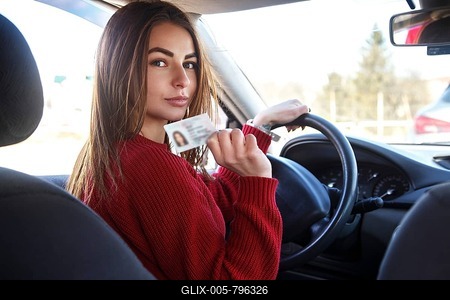 Joyful girl driving a training car with a drivers license card in her hands-stock-foto