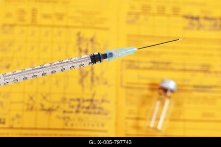 Vaccine concept with syringe in front of blurry vial and yellow international certificate of vaccination in background-stock-foto