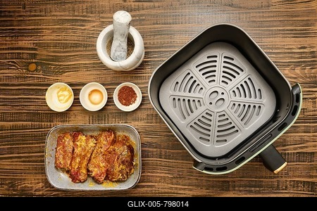 Marinated beef meat next to bowls of mustard, soy sauce, and spice blend on a wooden table. An air fryer sits ready for cooking, inviting delicious meal preparations-stock-foto