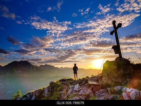 Mountaineer standing at sunset at the summit cross of the Brettgabel, in the background Watzmann, Hochkalter and Reiteralpe, Berchtesgaden Alps, Berchtesgaden National Park, Schönau am Königssee, Berchtesgadener Land, Bavaria, Germany-stock-foto