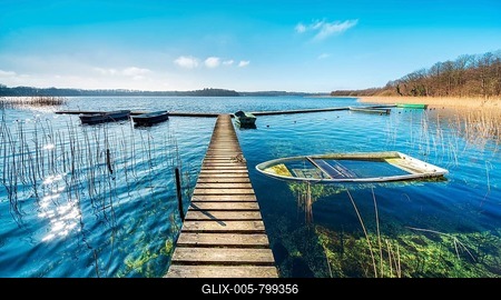 Clear sunny winter day at the Schaalsee, wooden jetty in the reeds with a rowing boat full of water, Schaalsee Biosphere Reserve, Mecklenburg-Western Pomerania, Germany-stock-foto