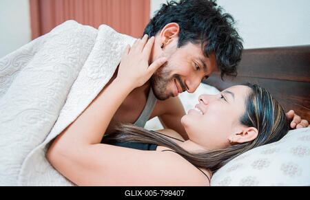 Couple waking up with a kiss in the morning, Man waking up woman with a kiss in bed. Couple in love in bed looking at each other with love-stock-foto