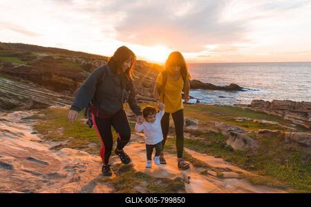 Lgbt couple of women with a child at sunset on the coast by the sea, family lifestyle-stock-foto