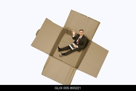 Businessman with a notebook sitting in a cardboard box-stock-foto