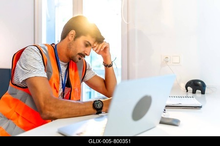 Young construction worker feeling stressed while working remotely from home using laptop, having problems and headache-stock-foto
