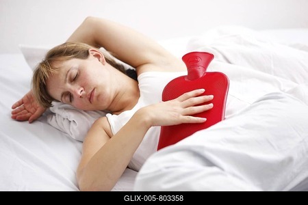 Woman has a stomachache, eases pain with a hot water bag, hot water bottle-stock-foto