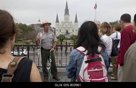 A ranger from Jean Lafitte National Historic Park and Preserve talks to tourists about the history of New Orleans while standing in front of Jackson Square and St. Louis Cathedral, New Orleans, Louisiana, USA-stock-foto