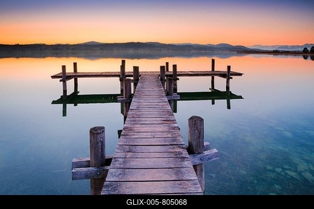 Wooden footbridge at the Pfäffikersee in backlight at sunrise with view to the Bachtel and Glärnisch in the background, Pfäffikon, Canton Zurich, Switzerland-stock-foto