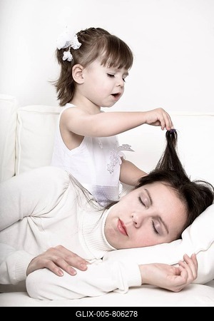 Little girl playing with the hair of her sleeping mother-stock-foto