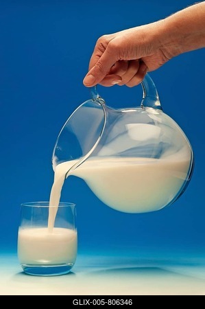 Hand pouring milk from a jug into a glass-stock-foto