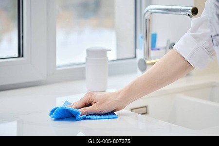 Female hand with washing sponge cleaning stone surface of kitchen tabletop (photo with shallow depth of field)-stock-foto