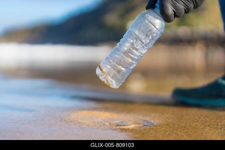 Hand of unrecognizable person picking up garbage or plastic on the beach. ecology concept-stock-foto
