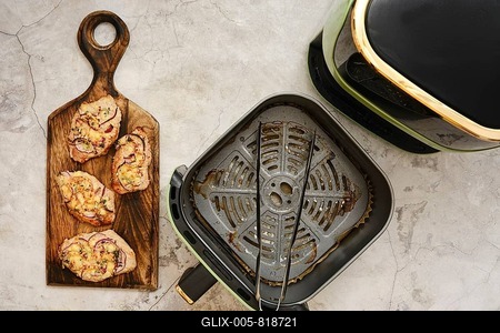 Juicy, golden-brown pork chops are arranged beautifully on a rustic wooden board, showcasing the perfect sear. An air fryer sits nearby, ready for more cooked delights-stock-foto