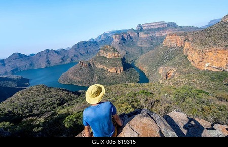 Young man sitting on a rock and enjoying the view, View of river bend at Blyde River Canyon with Three Rondawels peak, View of canyon with Blyde River and Table Mountains in the evening light, Canyon landscape, Panorama Route, Mpumalanga, South Africa-stock-foto