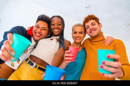 LGBT pride, lgbt rainbow flag, portrait of group of friends dancing and toasting with glasses in a house at party-stock-foto