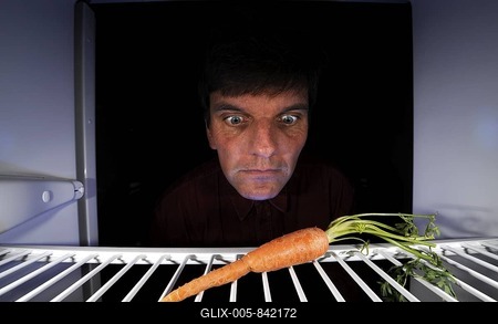 Man regarding a single carrot in an empty refrigerator-stock-foto