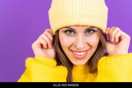 Close up portrait of young caucasian woman in yellow sweater isolated on yellow background, wearing wool cap-stock-foto