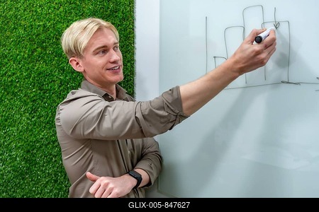 Young businessman drawing growing bar chart on whiteboard during a presentation in a modern office with a green wall-stock-foto