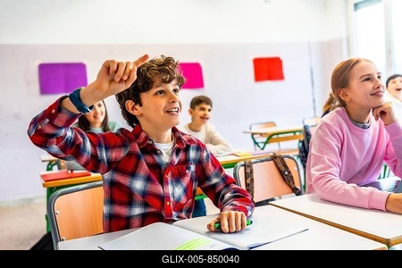Elementary school student raising hand to answer a question during class, showing eagerness to learn and participate in the classroom environment-stock-foto