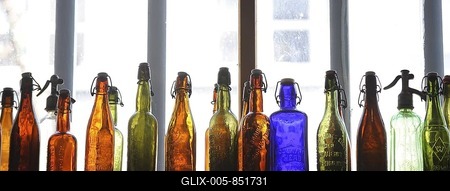 Colourful glass bottles in front of a window-stock-foto