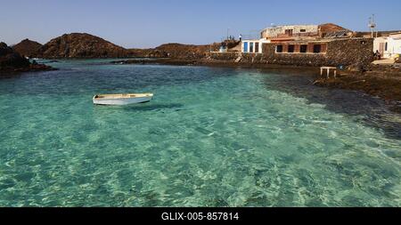 Harbour basin, boat floating on the water, crystal clear green sea, harbour building, north, Los Lobos Island, nature reserve, blue cloudless sky, Fuerteventura, Canary Islands, Spain-stock-foto