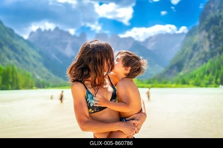 Mother embracing and kissing her son while enjoying summer vacation at lago di landro, surrounded by the breathtaking dolomites-stock-foto