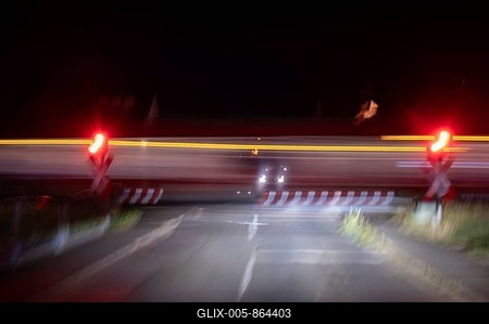 Passing train at a level crossing with barriers at night, Eckental, Middle Franconia, Bavaria, Germany-stock-foto