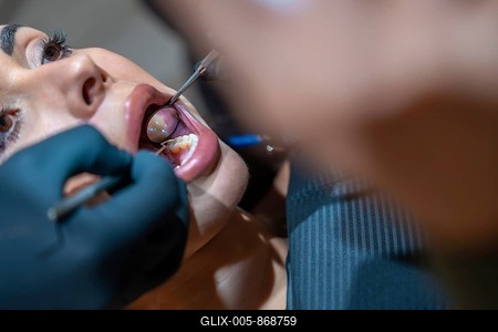 Dentist wearing black gloves using dental mirror and probe examining patient's teeth during consultation in dental clinic-stock-foto