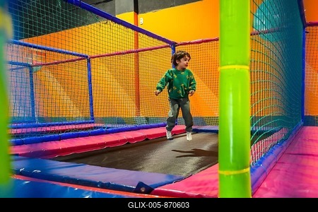 Young boy enjoying playtime, bouncing on a trampoline inside a vibrant and safe indoor play area-stock-foto