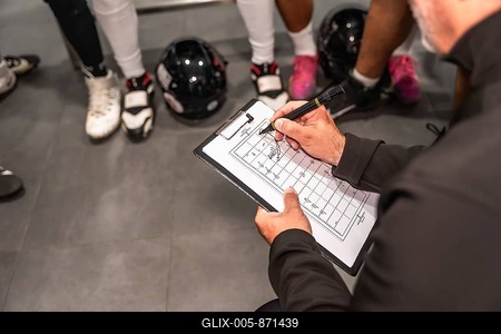 American football coach holding a clipboard, drawing strategies on a field diagram, instructing players in a locker room during a huddle, discussing tactics and game plan-stock-foto